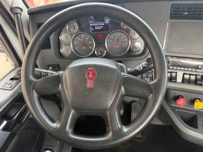 Kenworth T680 dashboard and steering wheel view showing instrument cluster, steering wheel with KW emblem, center console controls, and gauge faces.