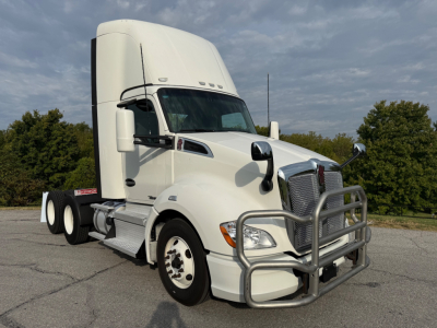 Kenworth T680 conventional daycab truck in white, front grille guard and bumper visible.