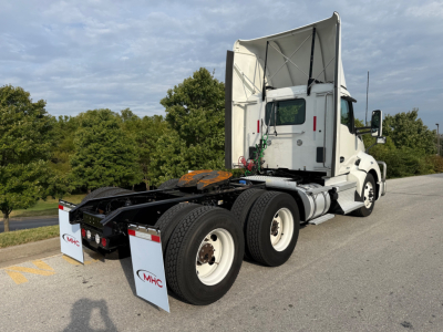 Kenworth T680 tractor truck seen from rear-three-quarter view with exposed fifth-wheel area and dual rear axles. Visible labels: MHC logos on mud flaps at rear.