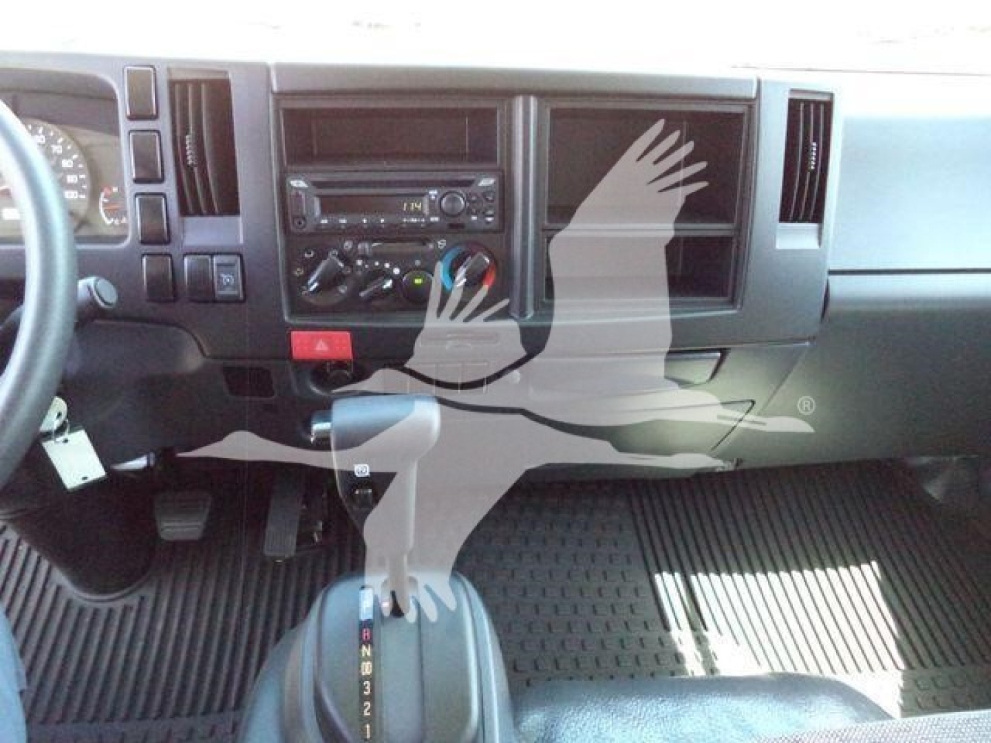 Isuzu NPRR dashboard and center stack showing climate controls and radio with manual gear selector visible