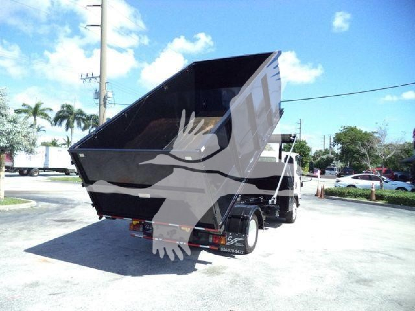 Isuzu NPRR dump truck bed in raised position showing rear view and dump body, black and white color scheme, truck bed in elevated angle.