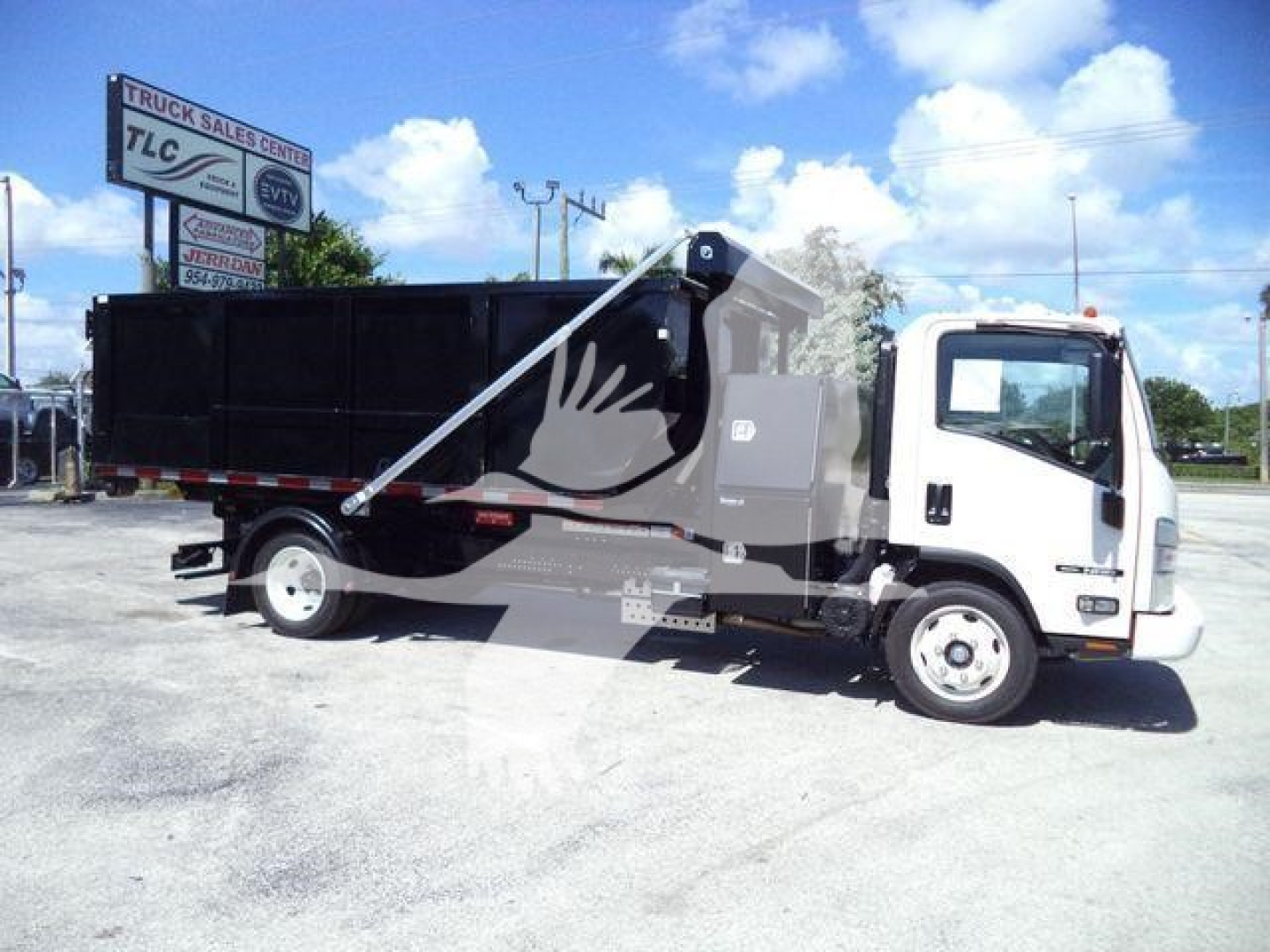 Isuzu NPRR roll-off truck in service bay photo showing cargo bed and hydraulic arm.