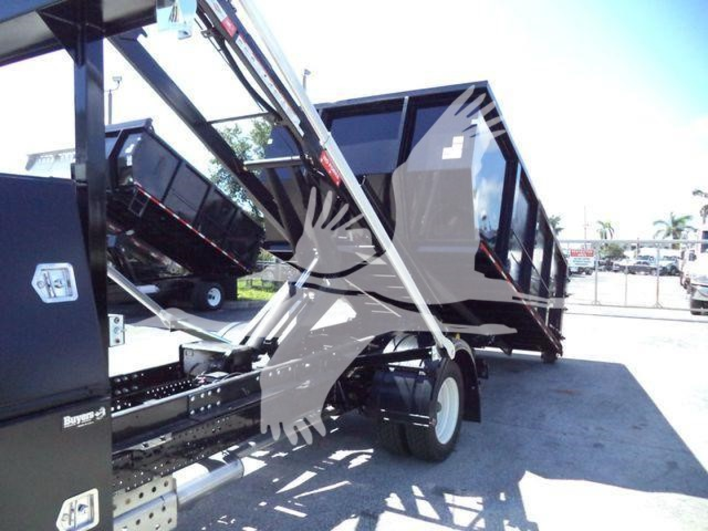 Isuzu NPR/RR roll-off truck with a tilted dump bed, showing hydraulic components and wheel, no visible license plate