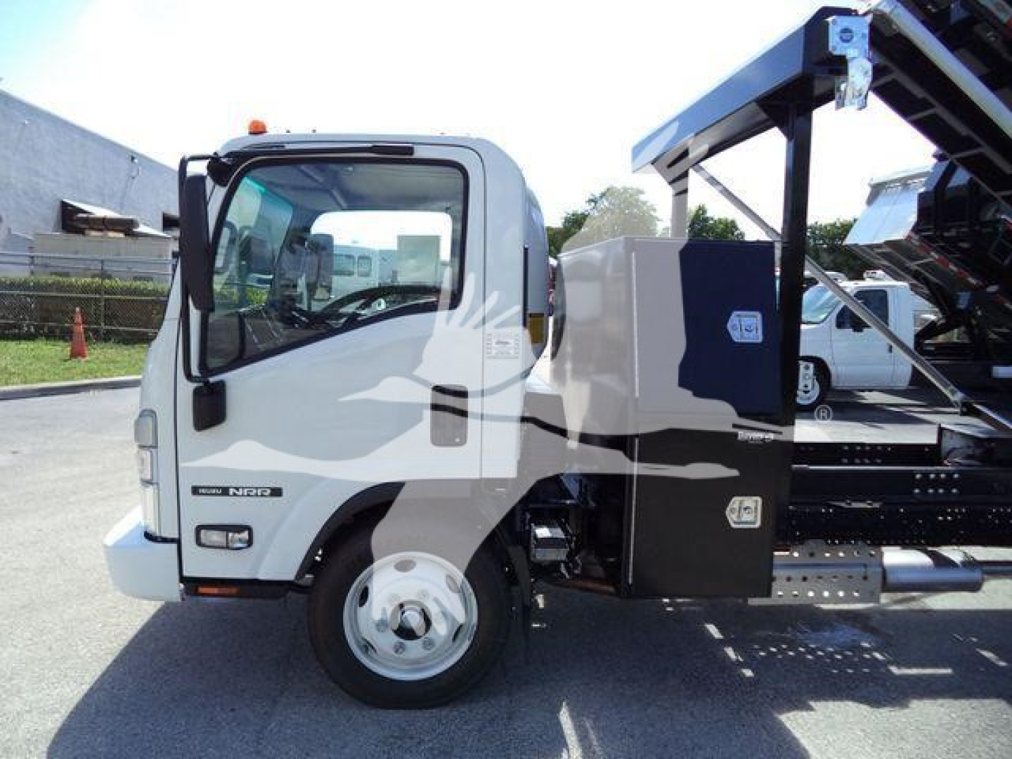 Isuzu NPR model truck with roll-off body, front view showing cab and side storage box, some branding and small text on door.