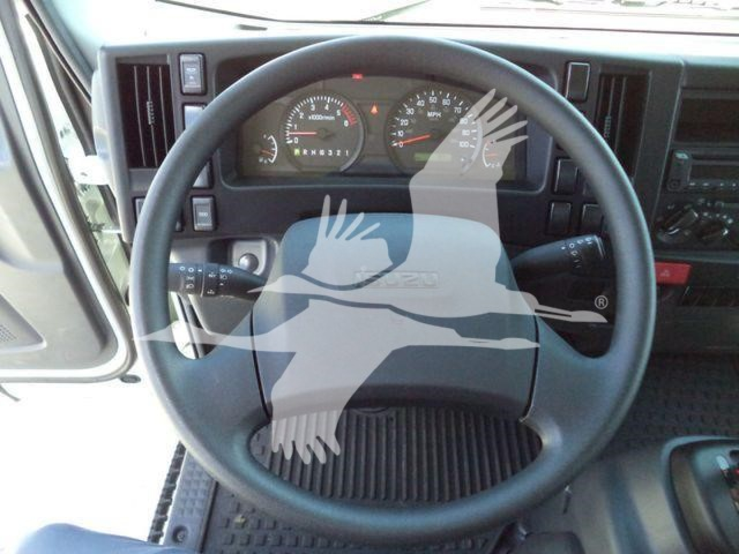 Isuzu NPRR steering wheel and dashboard view in a roll-off truck showing gauges and controls.