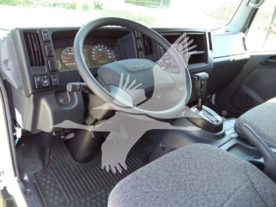 Isuzu NPRR cab interior showing steering wheel, dashboard with gauges, gear selector, and driver seat in a rolloff truck.