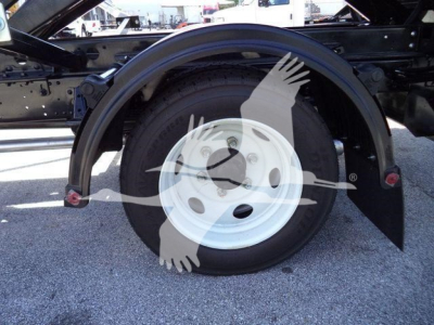 Isuzu NRR rolloff truck rear wheel assembly showing white steel wheel, tire, and fender with surrounding chassis components.