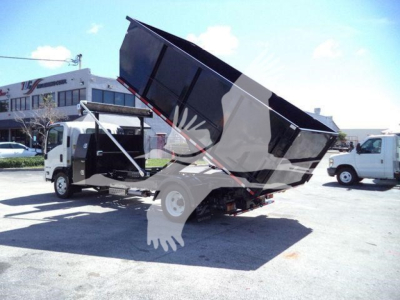 Isuzu NPRR rolloff truck with lifted dump bed in a dealership lot.