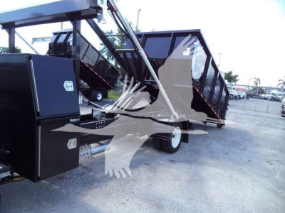 Truck body in-rolloff setup showing hydraulic lifting mechanism and cargo bed with black metal panels; mounting frame and wheels visible.