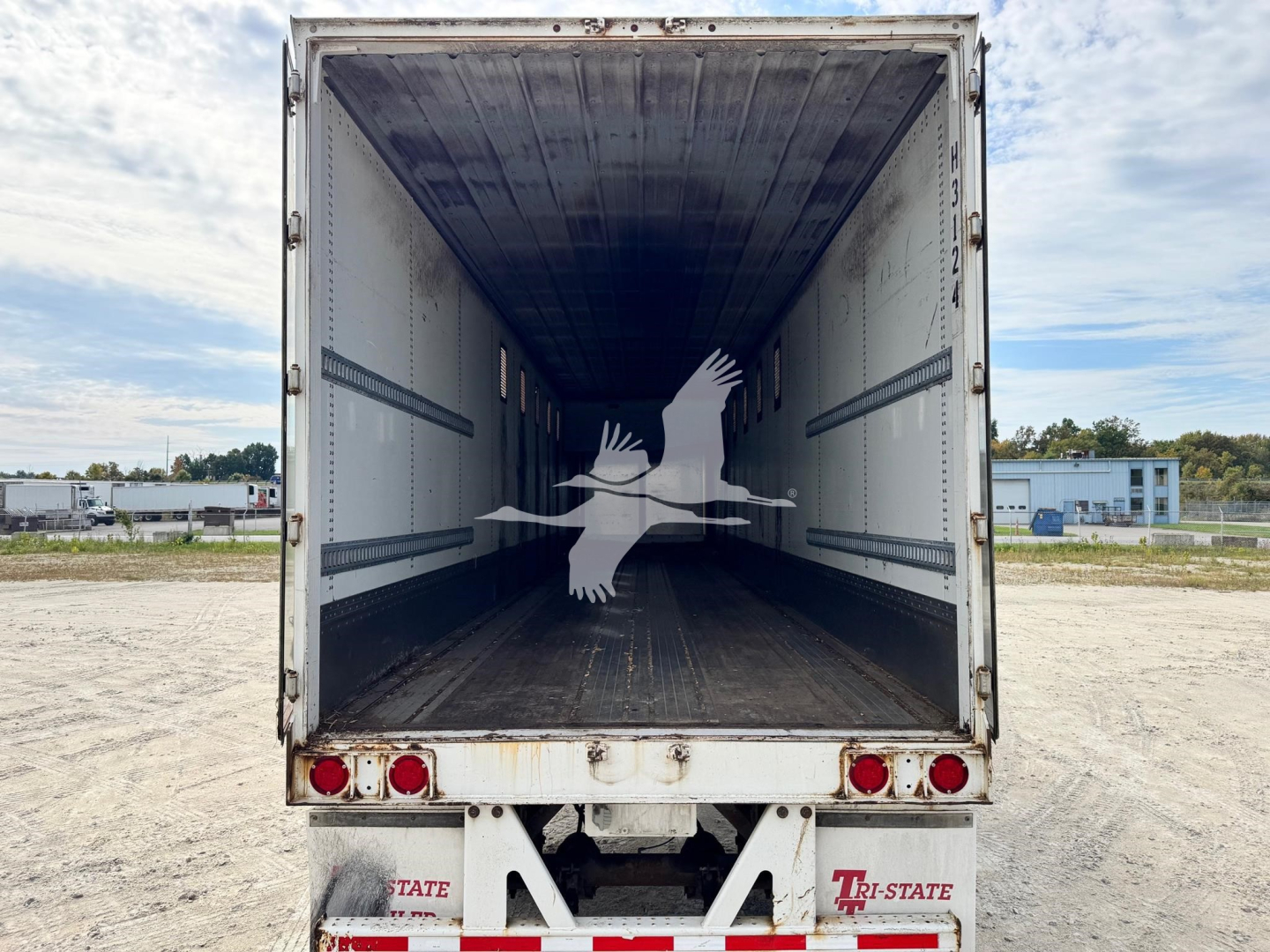 Trailer interior showing empty cargo space with white truck-trailer silhouette watermark. Exterior rear with taillights and bumper visible.
