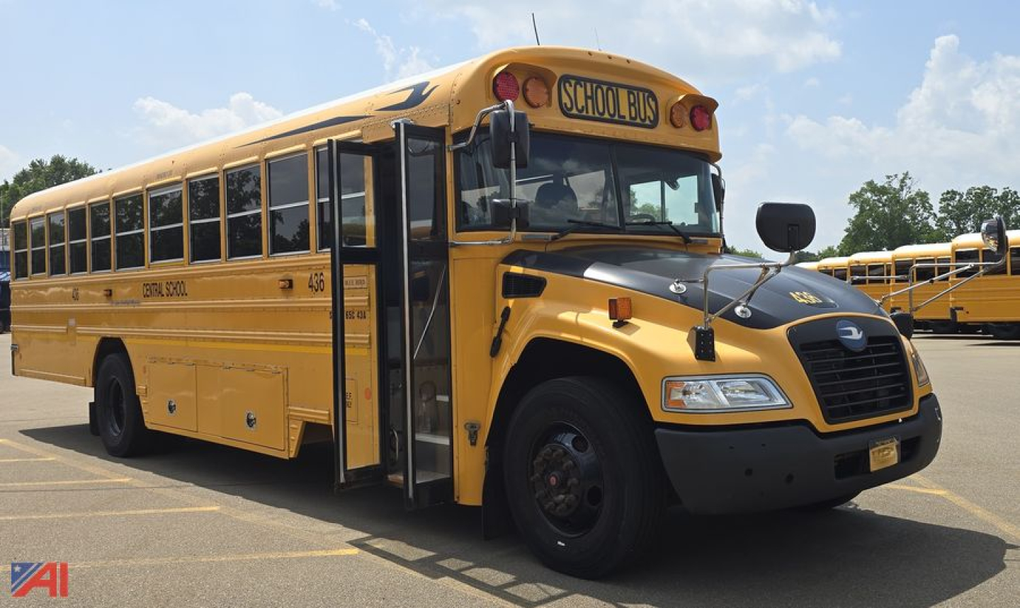 Blue Bird Vision school bus side view showing front end and open door, yellow body with 'SCHOOL BUS' sign on top.