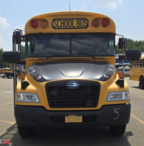 School bus front view with yellow body and gray hood showing 'SCHOOL BUS' sign and large windshield.