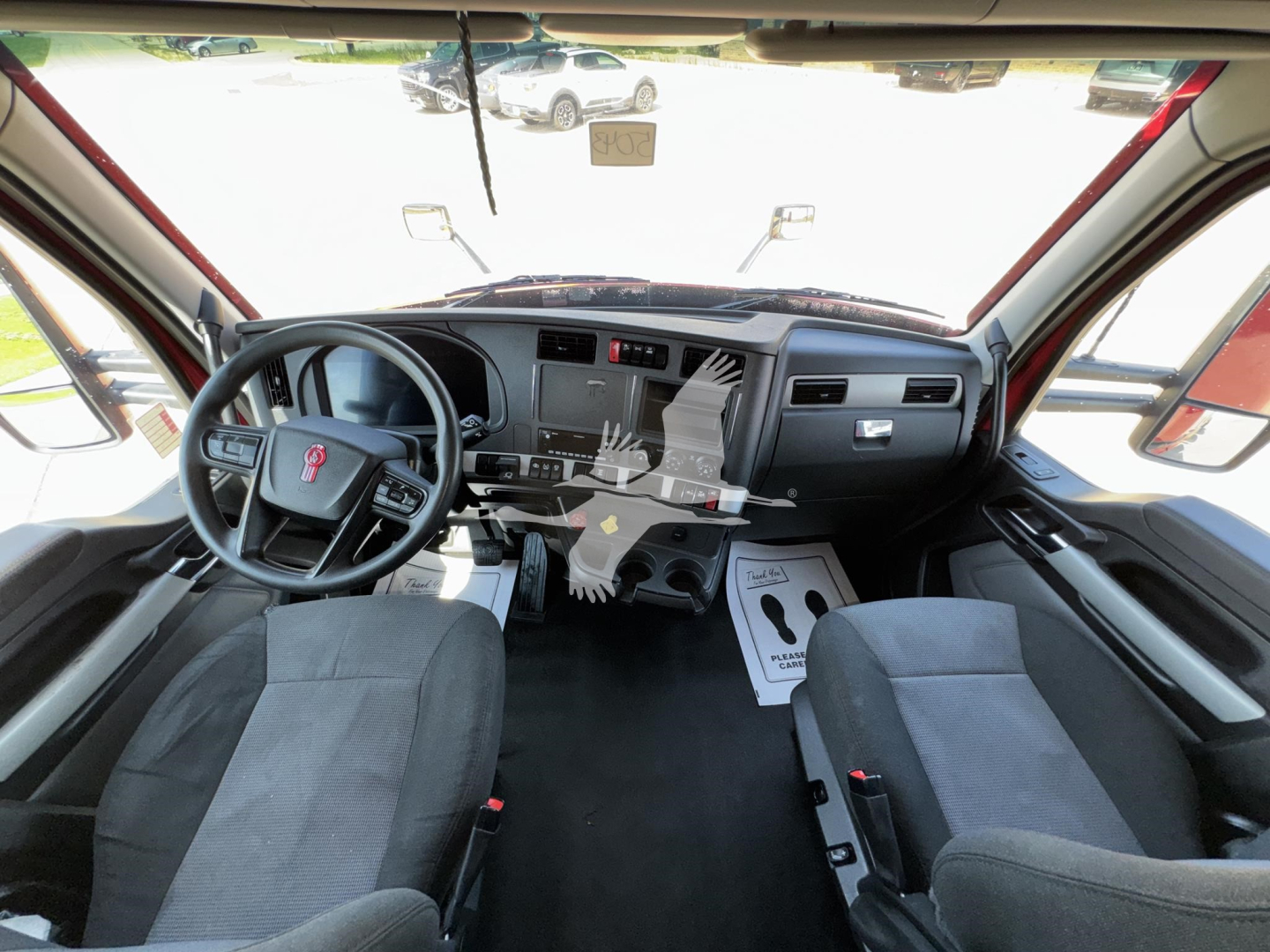 Truck cab interior of a 2023 Kenworth T680 showing dashboard, steering wheel, and cabin seating.