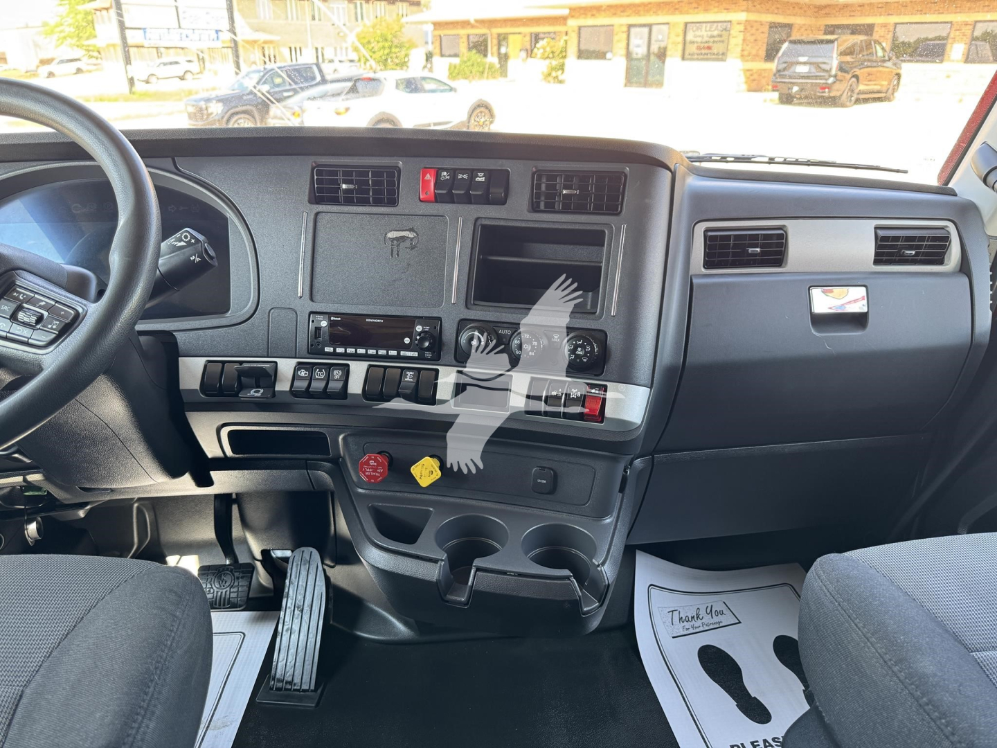 Kenworth T680 truck interior dashboard with steering wheel and center console, visible gauges, vents, switches, and cup holders.