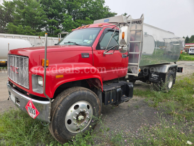 GMC C7500 dump truck with red cab and silver tanker, front grille with GMC emblem, dual rear wheels, front bumper with hazard placard; visible text includes 'T6000' on side step and '1993' on hazard plate; water tank trailer behind.