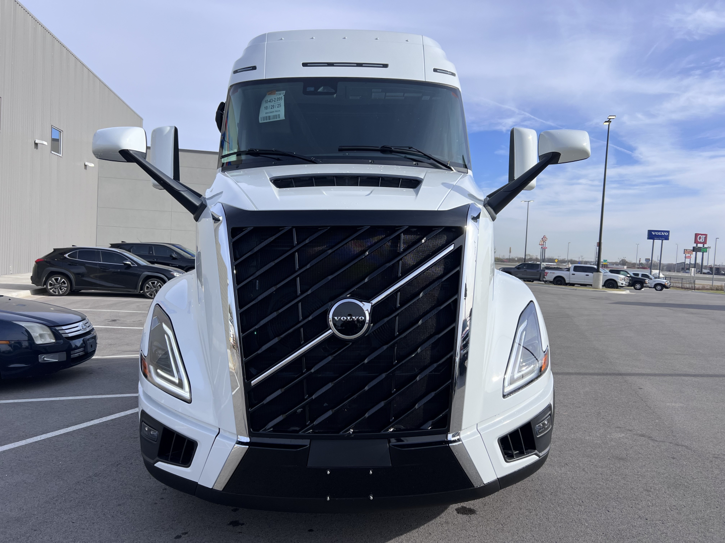 Volvo VNL64T840 truck front view with large black grille, Volvo emblem, angled headlights, side mirrors, and windshield.