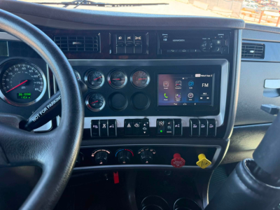 Kenworth T800W interior dash showing steering wheel, multiple gauges, and touchscreen infotainment unit.