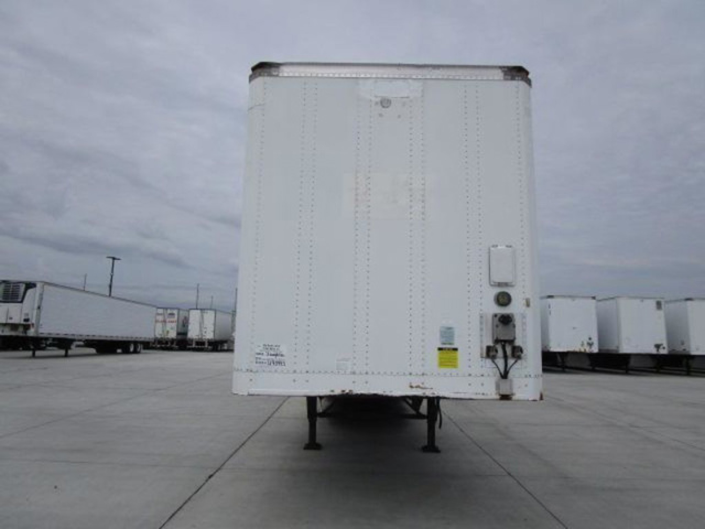 Trailer rear view of a 2014 Stoughton van trailer with landing gear raised, white exterior, and side door hardware visible.