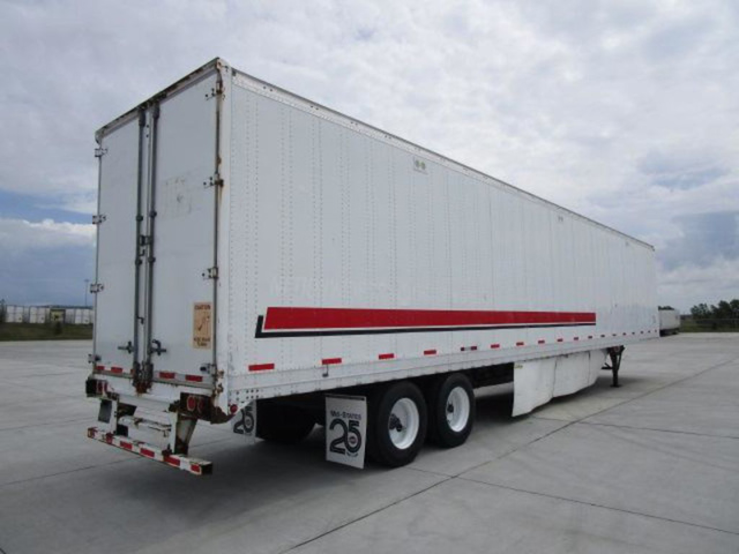 Stoughton van trailer showing side and rear with red stripe, triple axle, rear doors, and weathered white exterior.