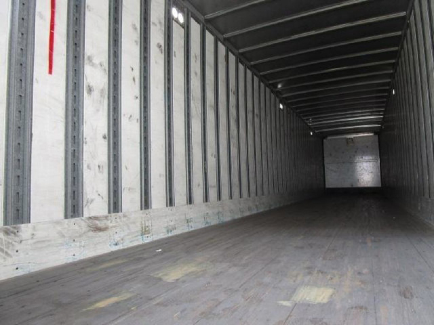 Trailer interior showing long empty wooden floor and metal side walls of a Stoughton van trailer.