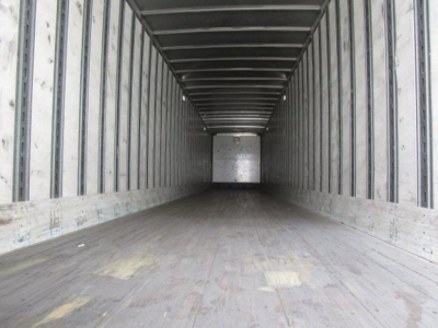 Trailer interior showing empty cargo space with wooden floor and metal sidewalls, viewed from near the front to rear.