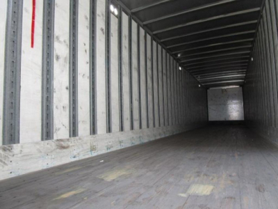 Trailer interior showing long empty wooden floor and metal side walls of a Stoughton van trailer.