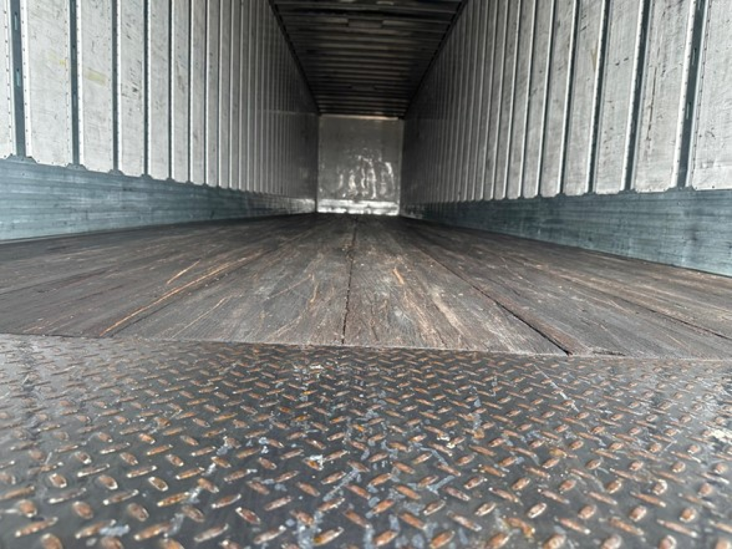 Trailer interior showing long empty cargo area with metal side walls and diamond plate threshold.