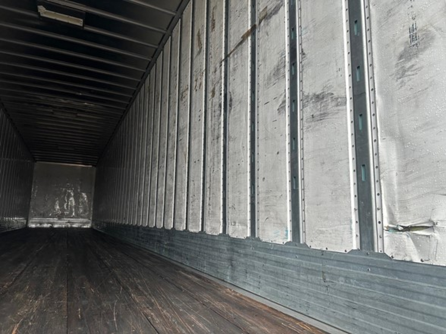 Trailer interior showing metal side walls with vertical ribs and a wooden floor inside a 2018 Utility 4000Dx trailer.
