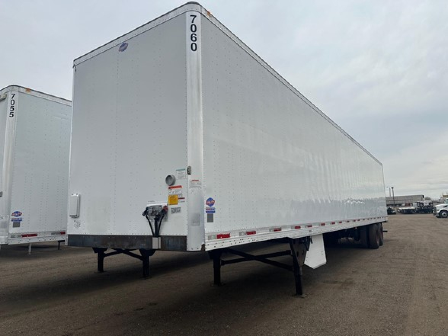 Utility 4000Dx trailer side and cab area showing a white enclosed box with rear and side doors, VIN tag area, and load-support legs visible.