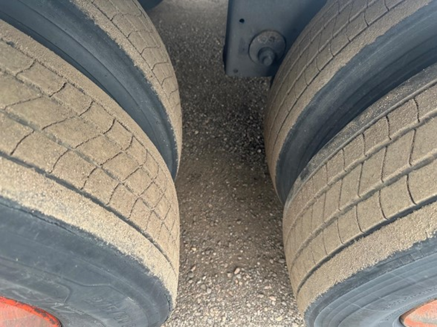 Trailer axle view showing twin tires with road grime and sand, part of a Utility 4000Dx trailer.