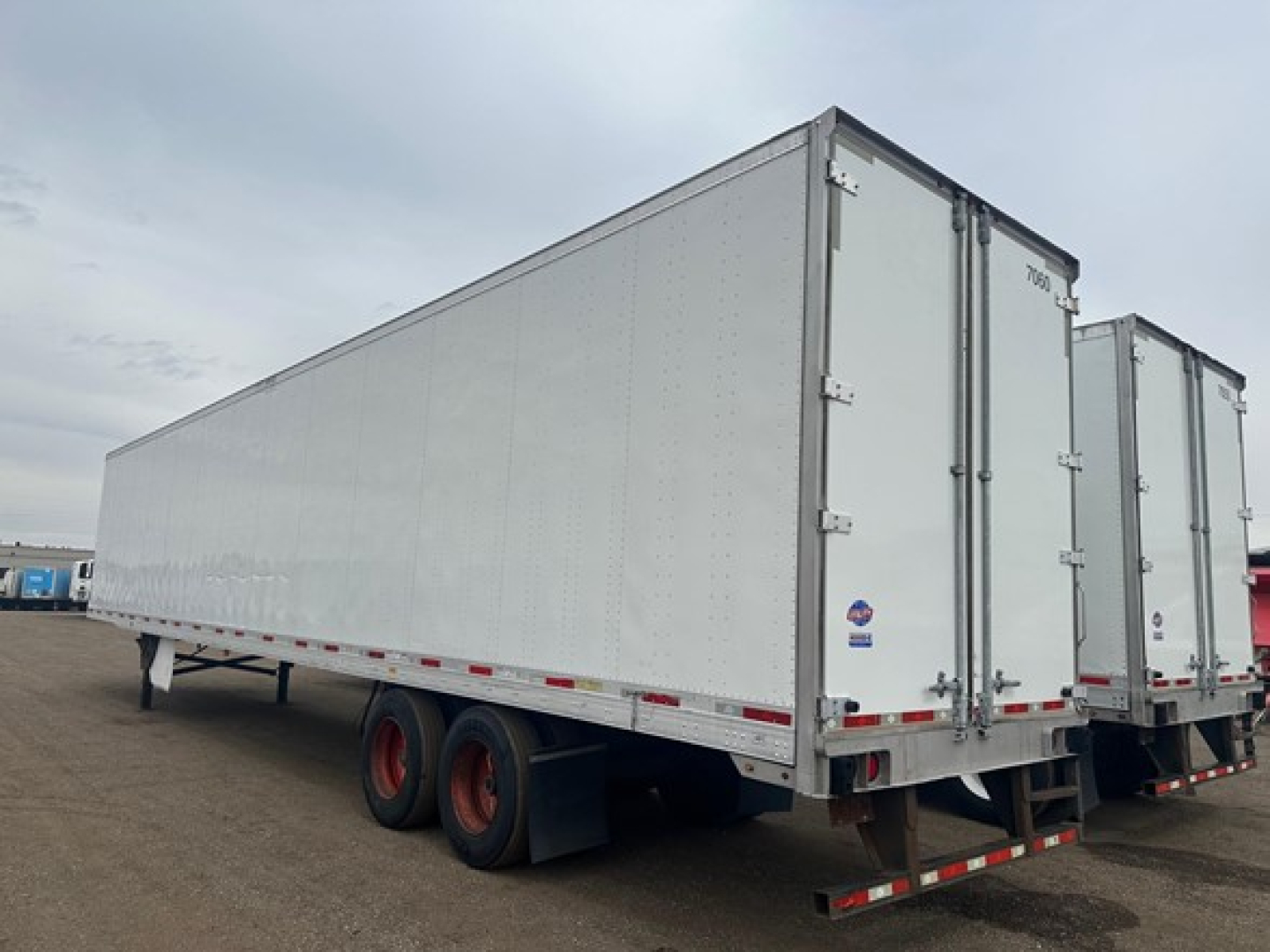 Utility 4000Dx trailer side view showing tandem rear axles and white riveted walls with rear doors.