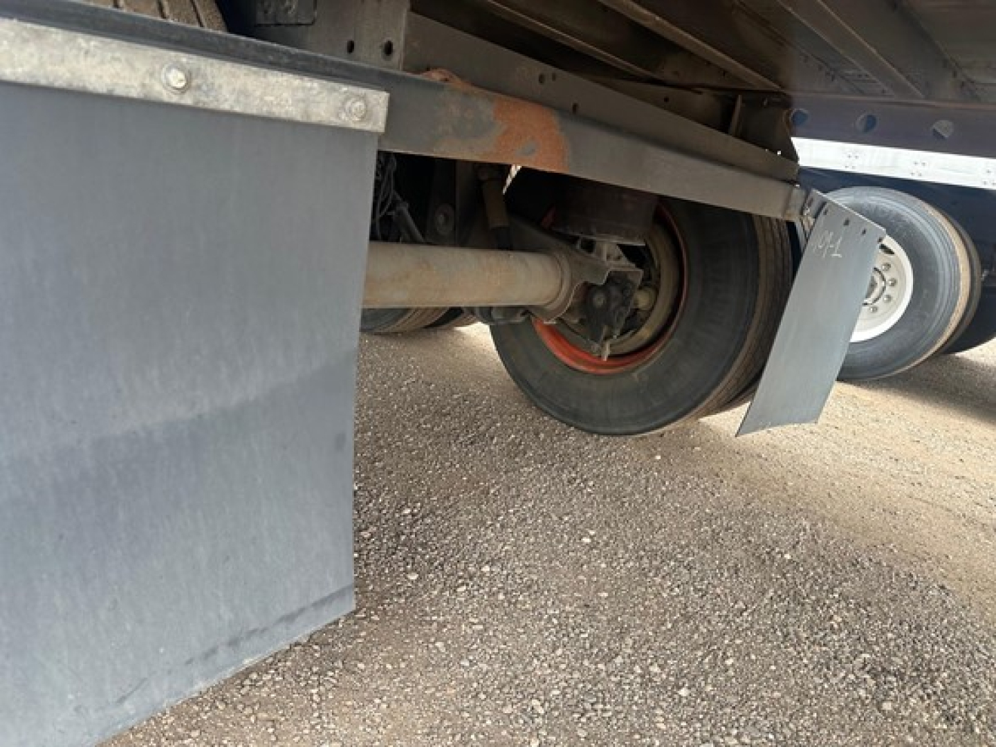 Underbody view of a Utility 4000Dx trailer showing wheels, axle, and suspension components with gravel ground.