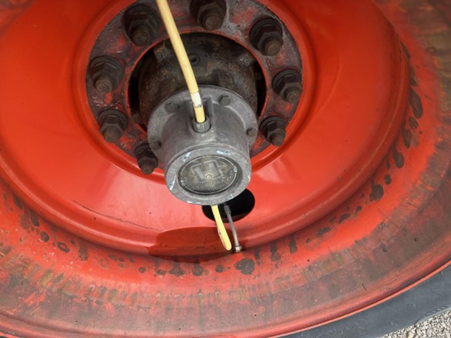 Trailer wheel hub and tire showing orange rim, central hub with four bolts, yellowCable attached, and black cover.