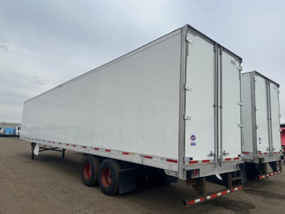 Utility 4000Dx trailer side view showing tandem rear axles and white riveted walls with rear doors.