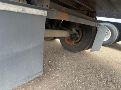 Underbody view of a Utility 4000Dx trailer showing wheels, axle, and suspension components with gravel ground.