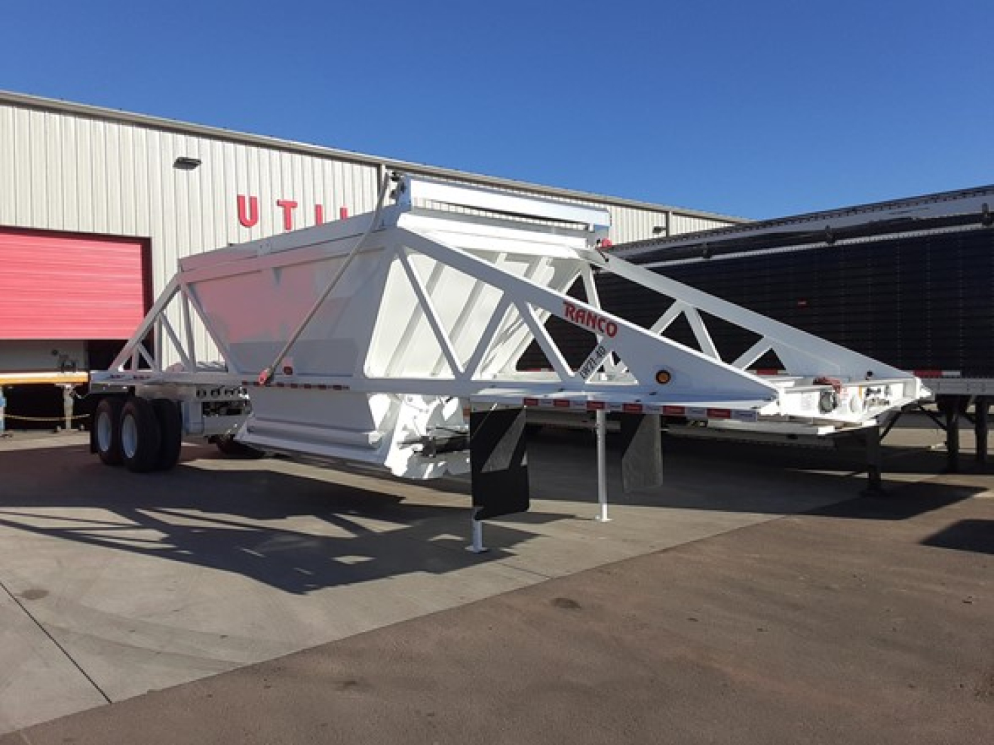 Ranco LW21-40 dump trailer showing dual-axle chassis and triangular frame, white with red branding.