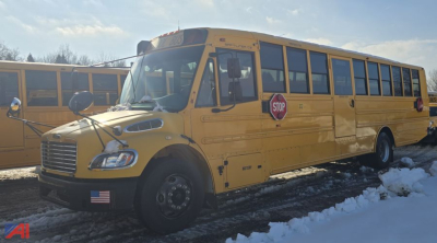 School bus side view showing a yellow Freightliner B2 school bus with stop sign and American flag decal near the front wheel.