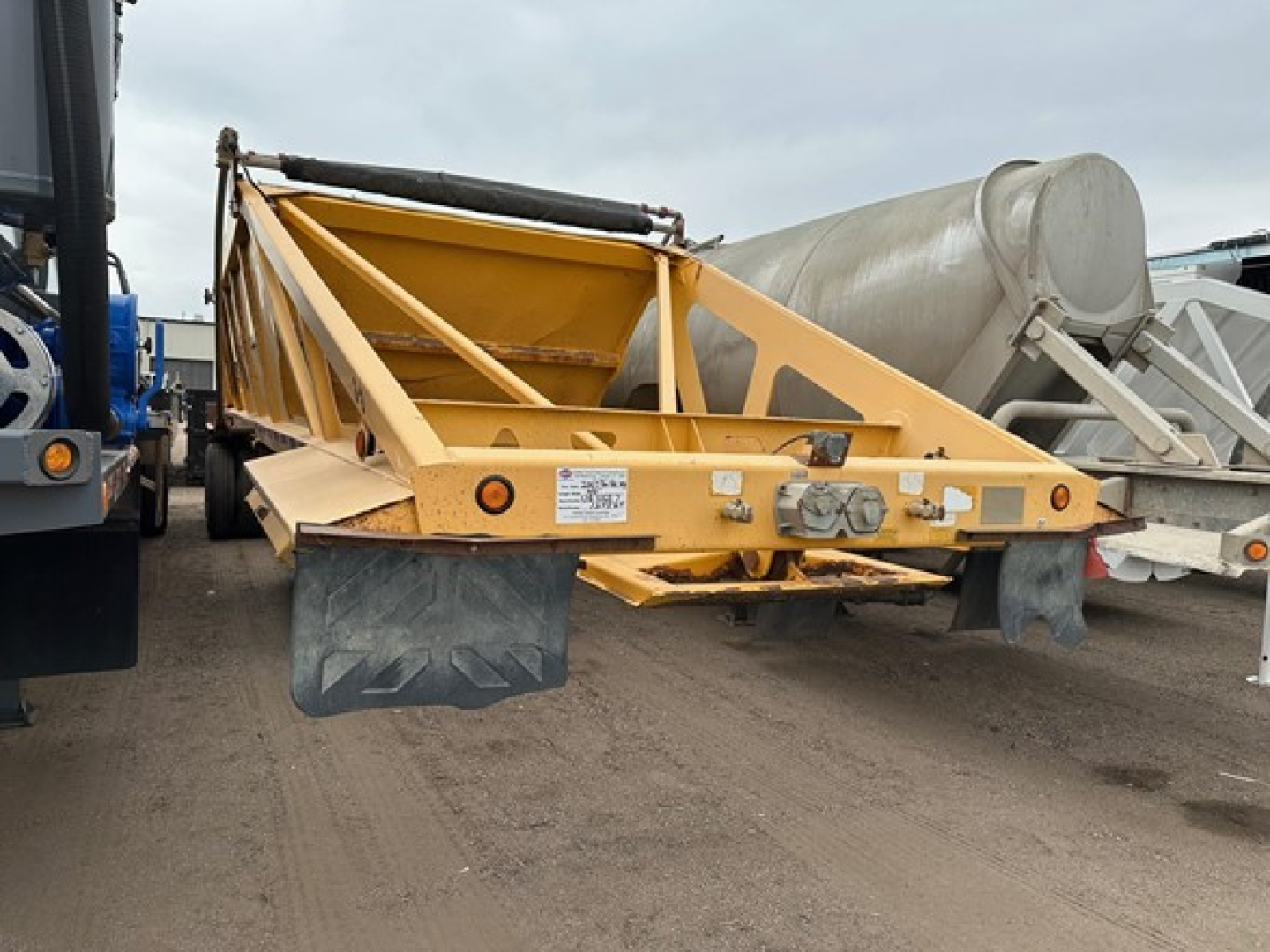 Bottom dump trailer with yellow frame, rear view showing load bed and tailgate, Trail King logo plate, reflectors, and mud flaps.