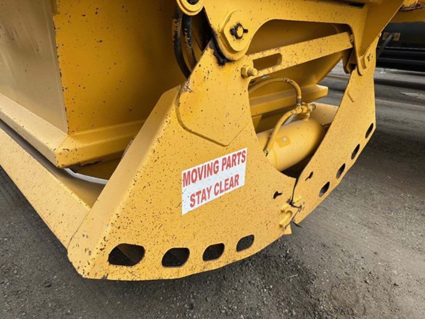 Trail King air ride bottom dump trailer yellow steel frame with moving parts label and hydraulic cylinder visible.