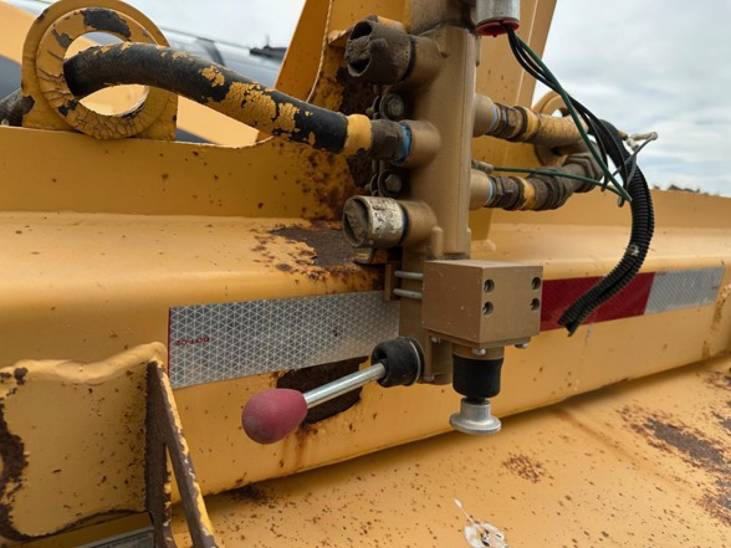 Trail King air ride bottom dump trailer hitching mechanism with hydraulic lines and control levers, showing rusted components and yellow paint.