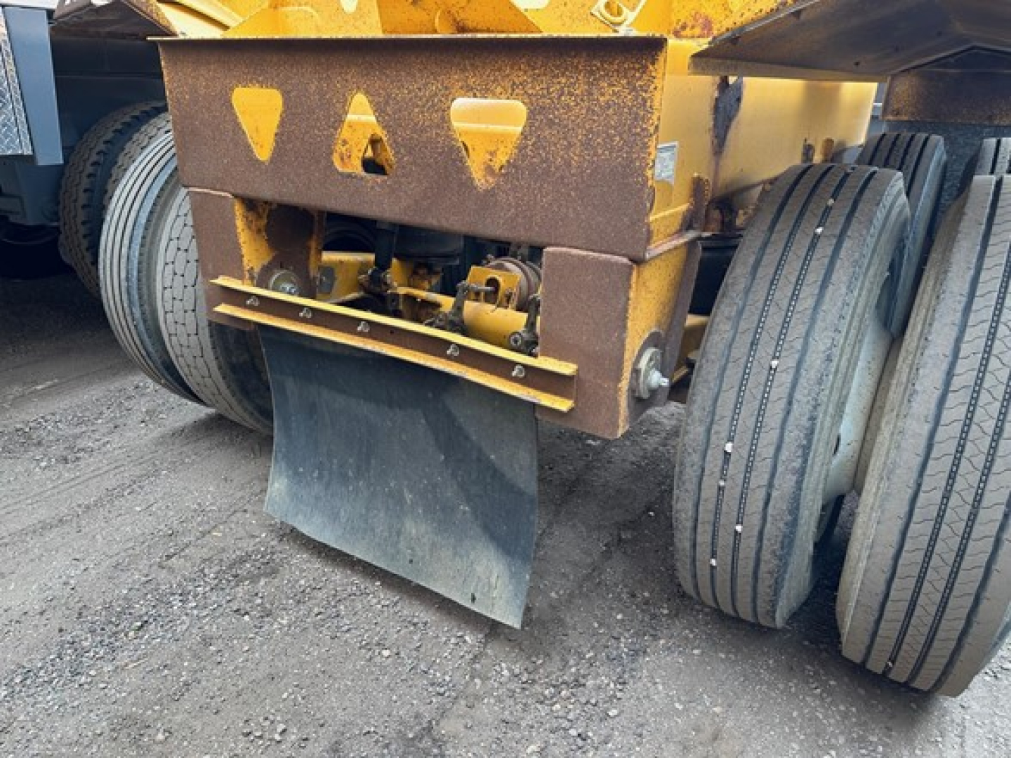 Heavy-duty Trail King air ride bottom dump trailer undercarriage showing dual rear axles, rusted frame, and dump blade/spoon hitch area.