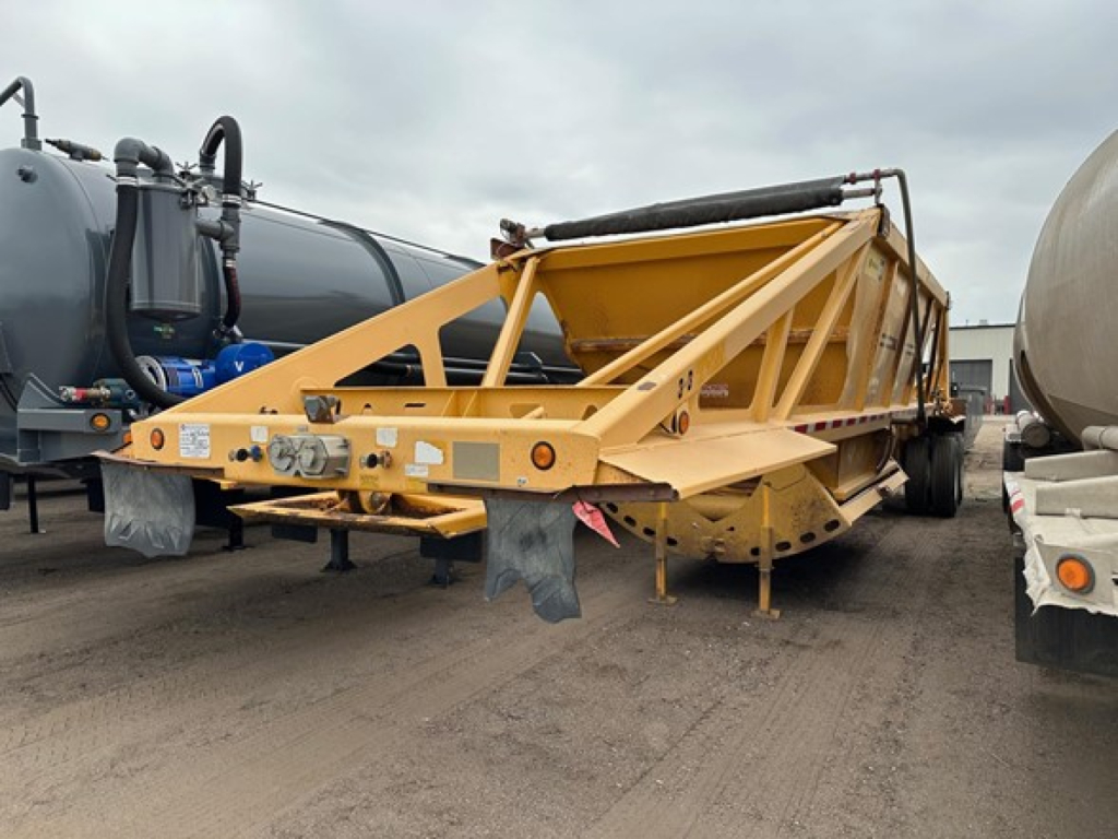 Trail King air ride bottom dump trailer showing yellow frame and rear tailgate with support braces and hydraulic components.