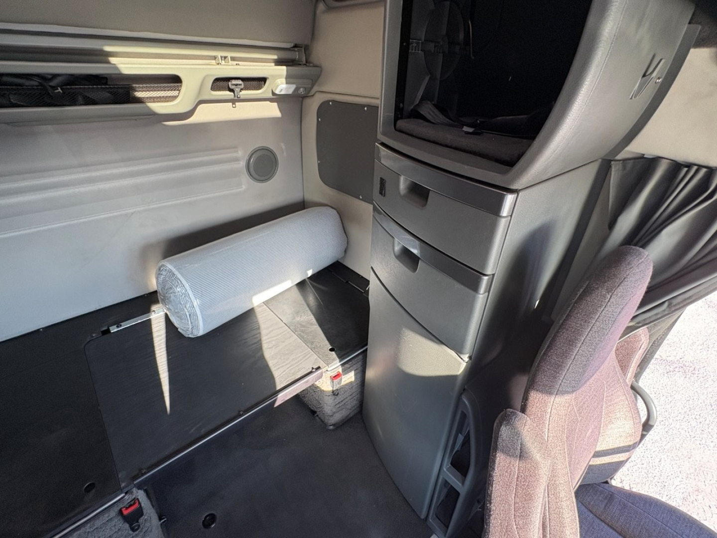 Volvo VNL64T860 cab interior view showing sleeper area with storage drawers, side panel, and seat in foreground.