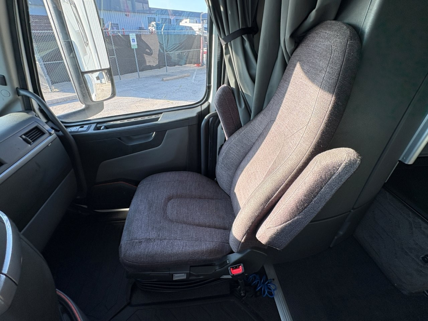 Volvo VNL64T860 cabin interior driver seat view with gray fabric seats and dashboard window area.