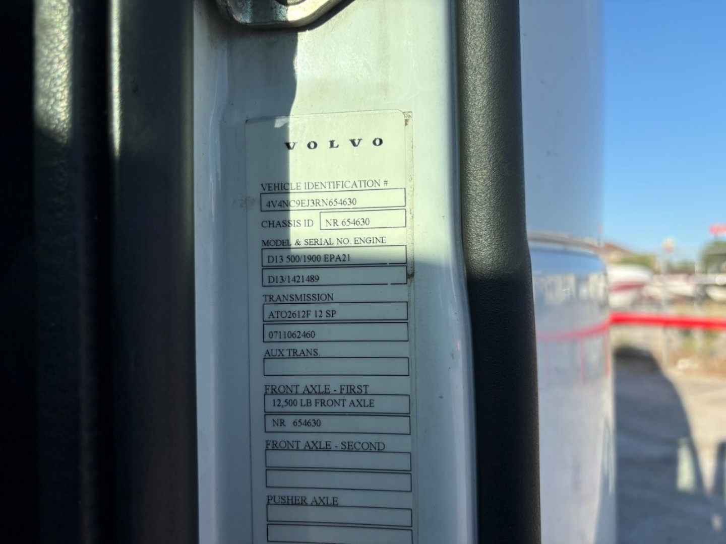 Volvo vehicle identification plate on a truck door frame showing VIN, class, model/serial, transmission, axles and front/rear axle data.
