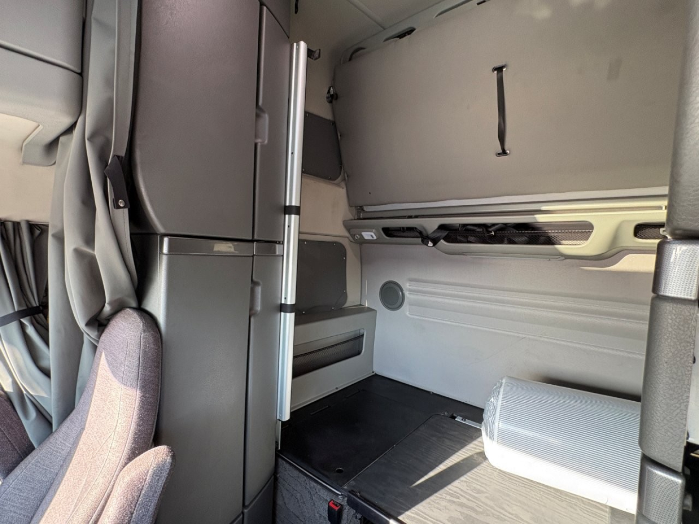 Vehicle interior cab area of a Volvo VNL64T860 showing sleeper area and storage panels.