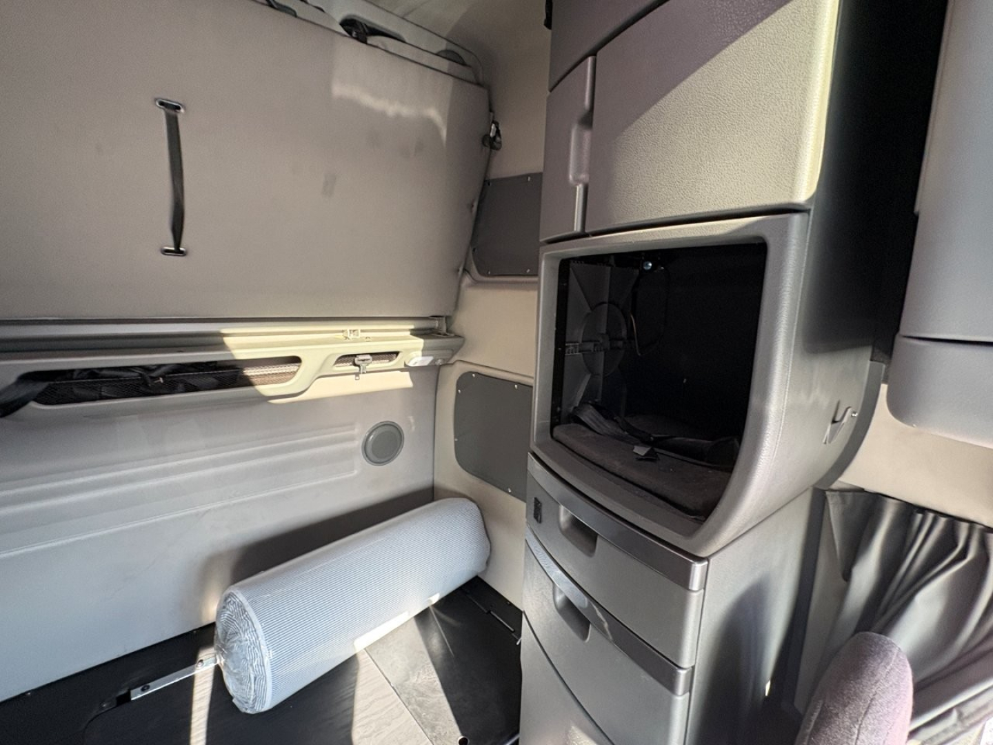 Volvo VNL64T860 sleeper cab interior showing dashboard console and open storage cavity with mounted shelves and cylindrical bolster.