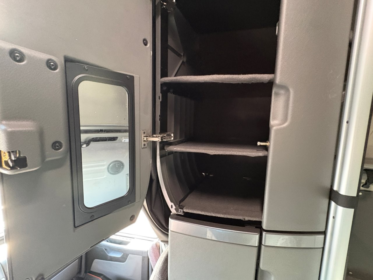 Volvo VNL64T860 sleeper truck interior showing open door and storage shelves with steps and windowed access