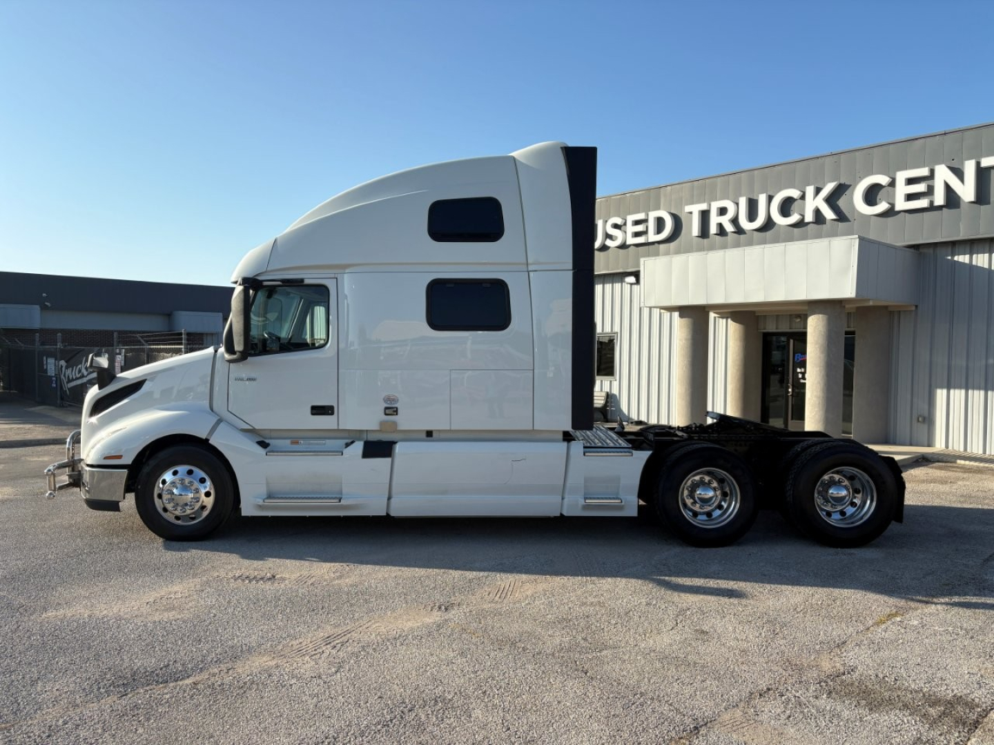 Volvo VNL64T860 semi-truck tractor in profile view showing sleeper cab and dual rear axles at a used truck center.