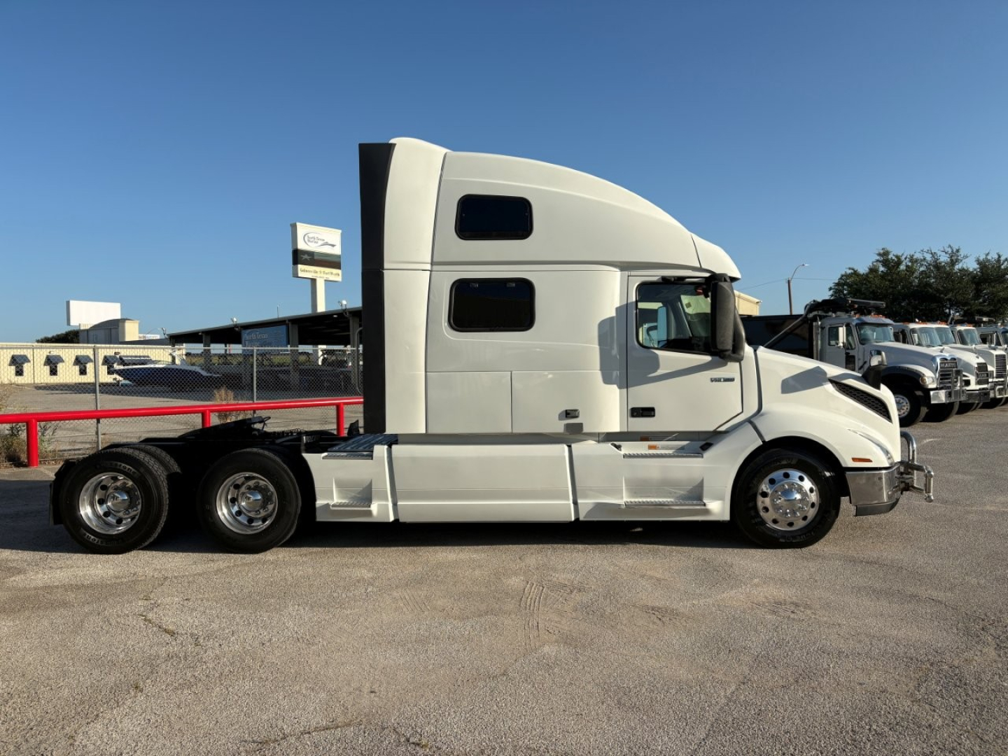 Side view of a white Volvo VNL64T860 truck sleeper cab with dual rear axles, chrome wheels, and windows; no legible branding text visible.